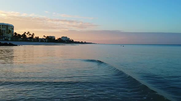 Flying above the waves at the Naples beach with a beautiful sunrise and pelicans in the distance