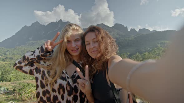 Two Young Women Photographed Against the Mountain View Enjoying Their Vacation Travel Adventure