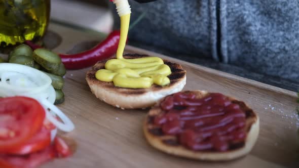 Making Burger  Spreading the Mustard Sauce on a Half of Grilled Burger Bun