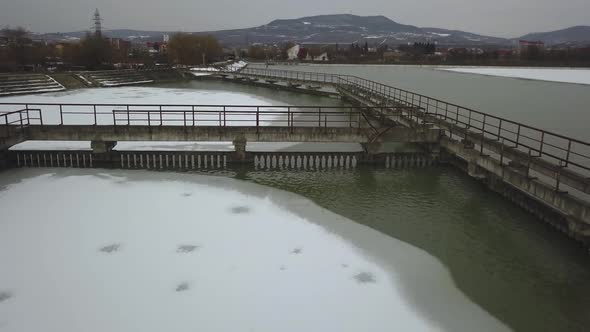 Frozen lake in winter, aerial drone shot from above, concrete walkways in lake, dark, cloudy and moo