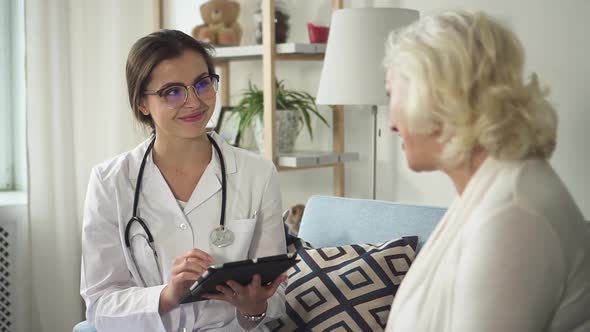 Doctor with Tablet Visiting Senior Woman at Her House