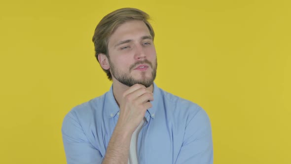 Pensive Young Man Thinking and Getting Idea on Yellow Background