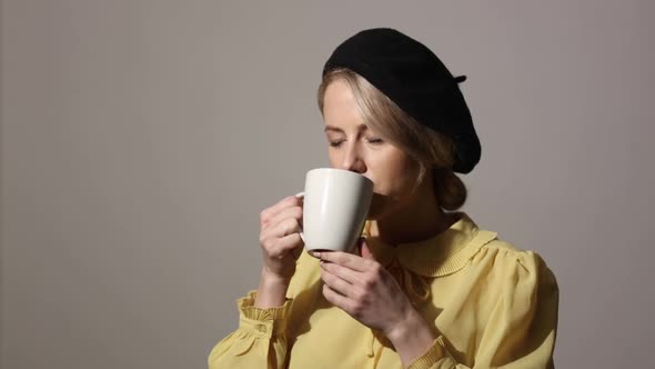 Stylish woman with cup of coffee on grey background