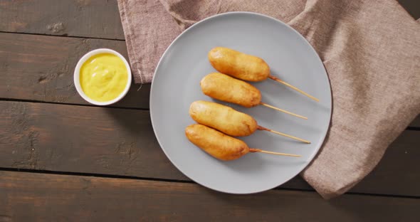 Video of corn dogs with dips on a wooden surface