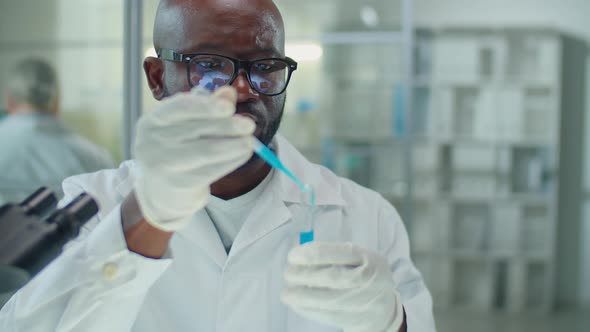 African American Lab Scientist Pouring Blue Liquid Chemical in Test Tube