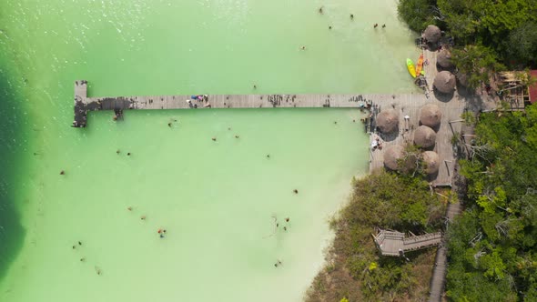 Aerial Birds Eye Overhead Top Down Zooming View of Wooden Pier Above Pastel Green Water