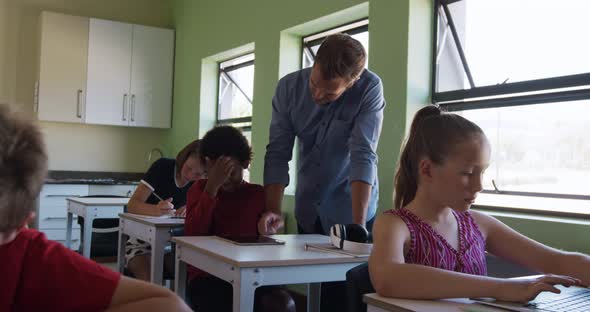 Male teacher and girl using digital tablet in the class