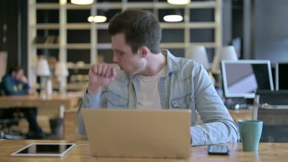 Sick Young Male Designer Coughing in Modern Office