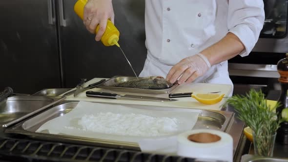 The Chef Pours Olive Oil on the Fish Before Cooking in a Professional Kitchen