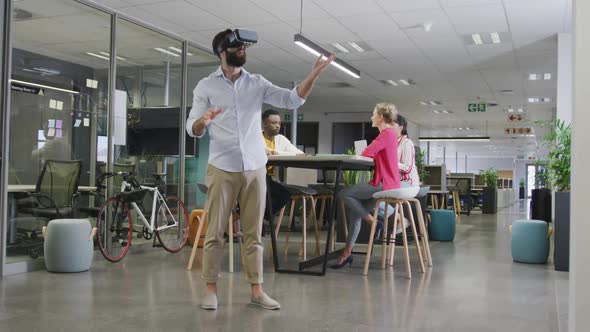 Happy biracial businessman using vr headset over colleagues in office