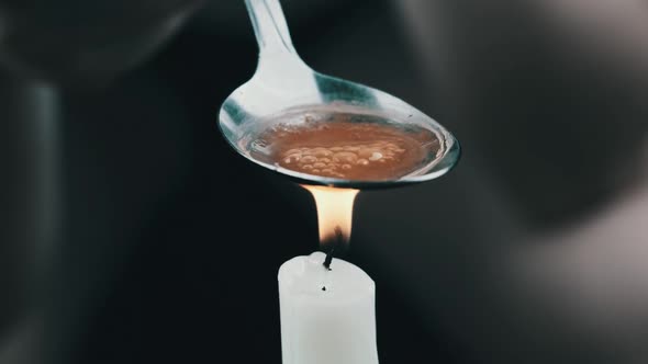 Preparing a Dose of Heroin in a Spoon Over a Candle Flame