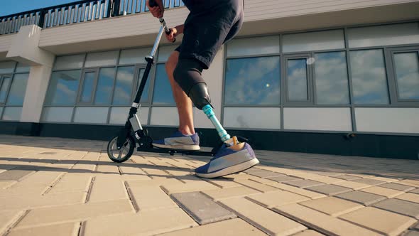 Athlete with a Prosthetic Leg Is Riding a Scooter