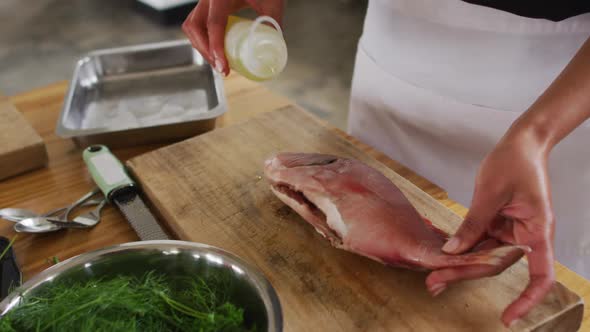 Caucasian female chef preparing a dish and smiling in a kitchen