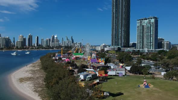 Aerial view of a colourful carnival situated by the sea with a city skyline in the background