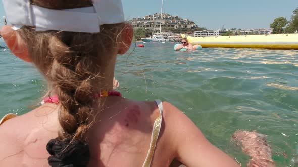 Girl With Mother On Inflatable Rings