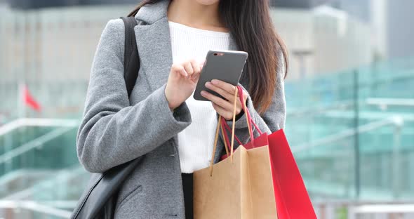 Woman use of mobile phone and holding shopping bag