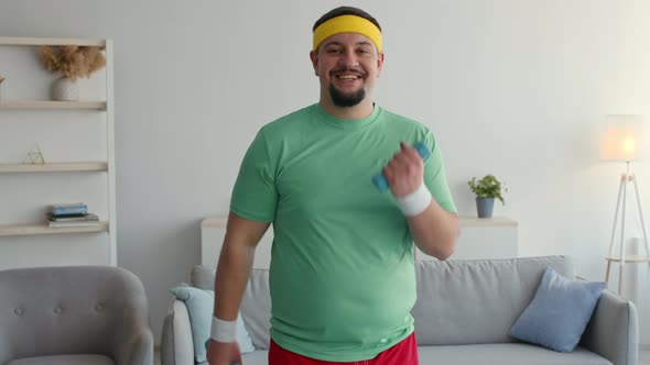 Happy Overweight Man Enjoying Fitness Activity at Home Exercising with Dumbbells and Smiling to