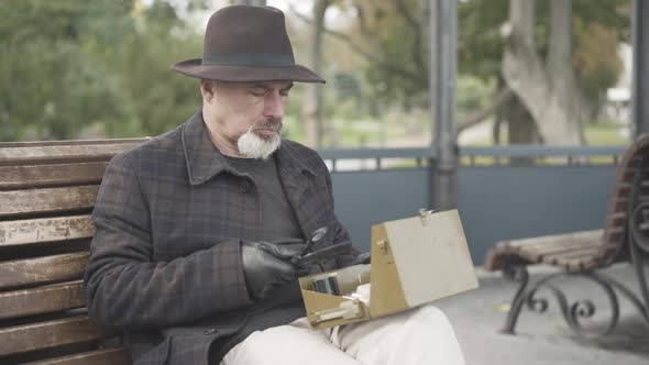 Serious Handsome Caucasian Spy or Intelligencer Examining Box with Novichok Using Magnifying Glass