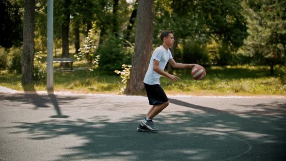 Young Man Playing Basketball on the Sports Ground with Friends - Dribbling, Avoiding His Opponents -