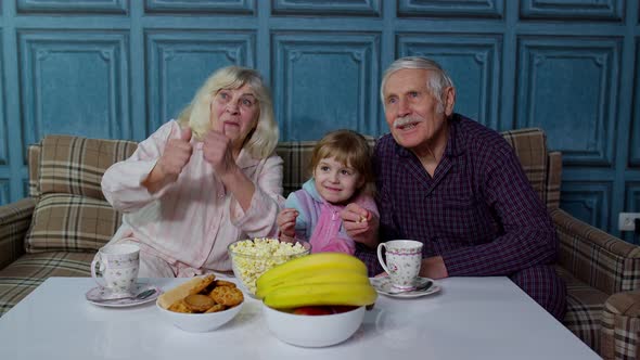 Senior Grandfather and Grandmother Eating Popcorn and Getting Scared Watching Horror Movies at Home