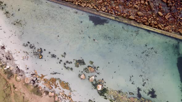 Aerial view of woman swimming in Glencairn pool, Cape Town, South Africa.