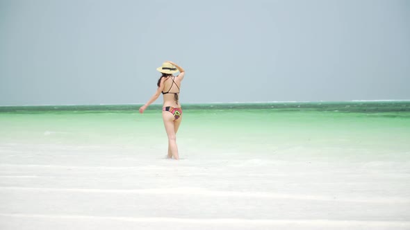 Young Woman Walks Barefoot On Beach Along Ocean