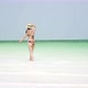 Young Woman Walks Barefoot On Beach Along Ocean - VideoHive Item for Sale