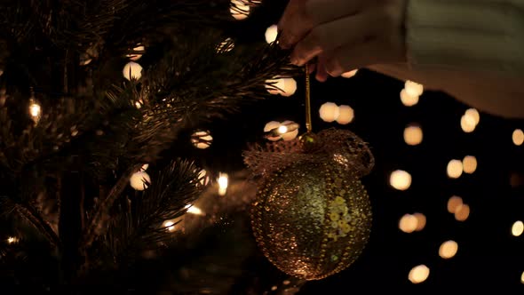 Woman Hanging Christmas Ball On Tree