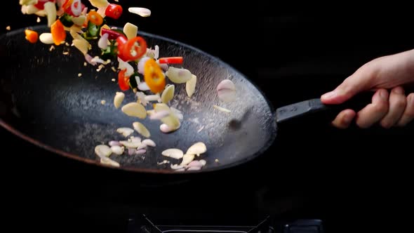 Slow Motion of Chopped Chili and Onion Tossing Up With a Cooking Pan With Black Backdrop