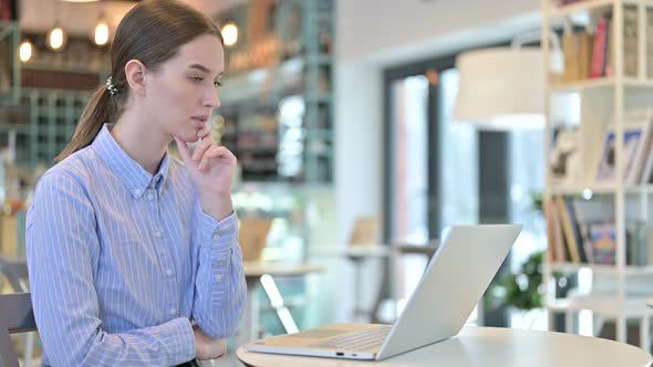 Thoughtful Young Businesswoman Using Laptop in Cafe