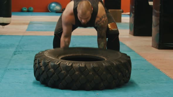 A Man Bodybuilder Flips Over a Big Tire