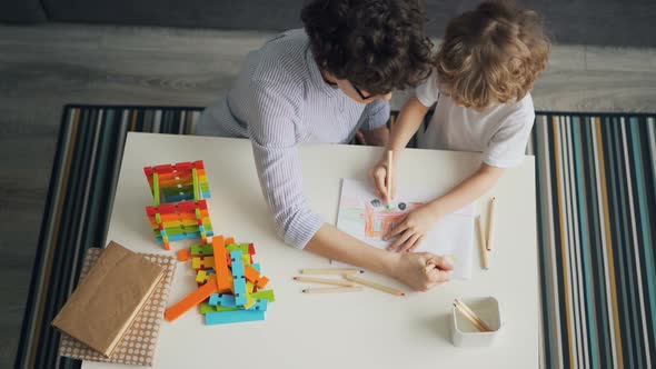 Young Woman and Child Drawing Together Making Picture with Pencils in Flat