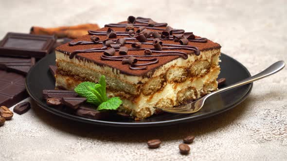 Portion of Traditional Italian Tiramisu dessert and pieces of chocolate bar