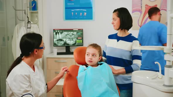 Doctor Showing to Child the Correct Dental Hygiene Using Mockup of Teeth Skeleton