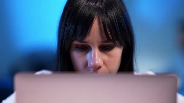 Closeup Face of Focused Beautiful Young Woman Over Laptop Looking at Camera