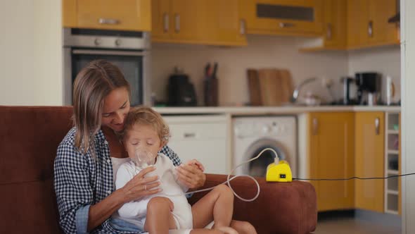 Baby Boy Breathes Through an Inhaler or Nebulizer While Sitting in His Mother's Arms