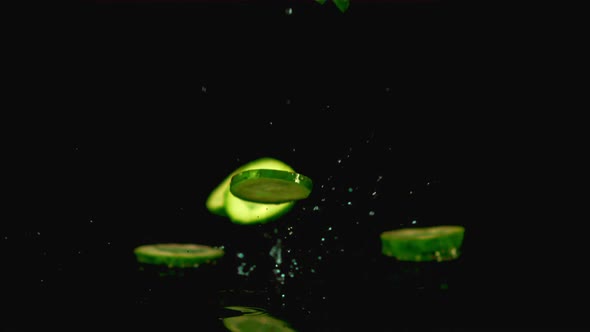 Super Slow Motion Pieces of Fresh Cucumber Fall on the Water with Splashes