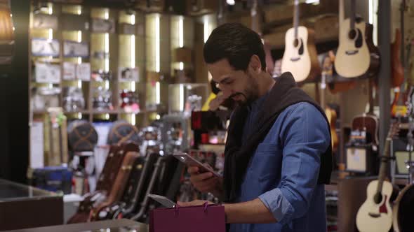 A Middle Eastern Man Using Mobile Phone To Purchase Product 