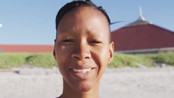 African American woman looking at camera and smiling on the beach and blue sky background