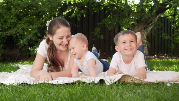 Happy Children with Mother Lying on Grass and Smiling in Camera