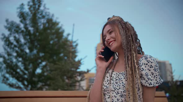 Young and Beautiful Girl Talking on a Smartphone in the Street