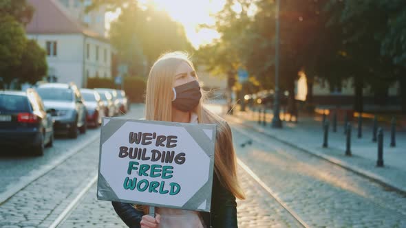 Blonde Woman in Protective Mask Holding Streamer with Slogan "Building Free World"