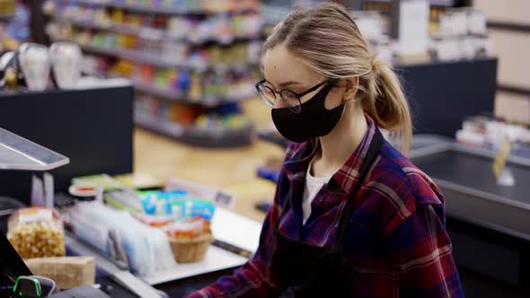 Female Cashier in a Protective Mask Pierces the Products with the Scanner