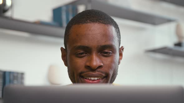 Smiling african freelancer man working on computer at home
