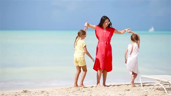 Adorable Little Girls and Young Mother Having Fun on White Beach