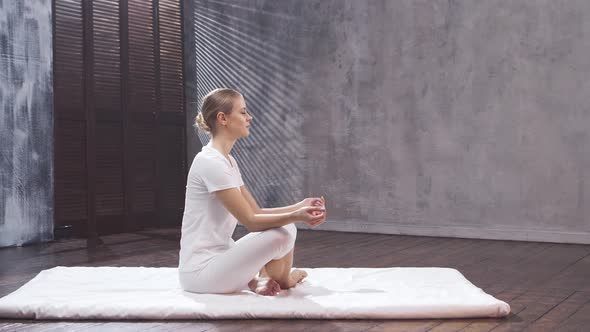 Young and fit woman is practicing yoga indoor in the class. Stretching exercise.