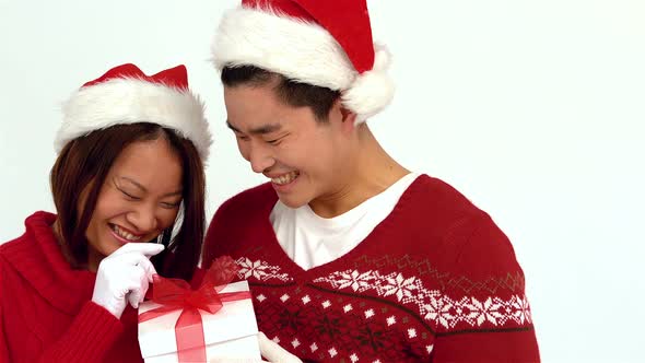 Festive Asian couple holding Christmas present and smiling