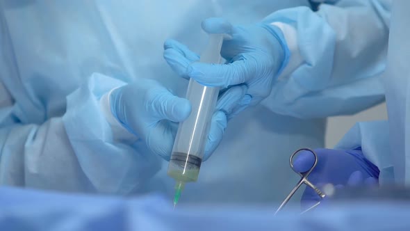 Medical Worker Injecting Medication by Syringe During Operation, Health Care