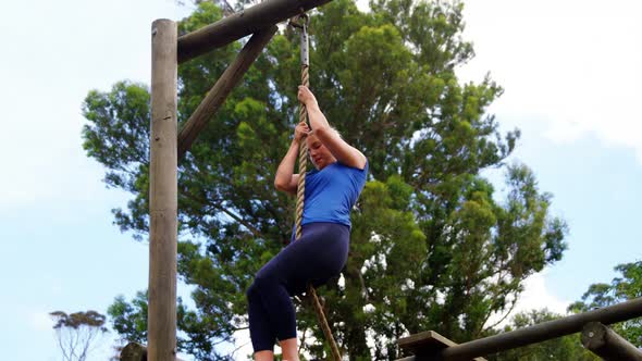 Fit woman climbing down the rope during obstacle course 4k