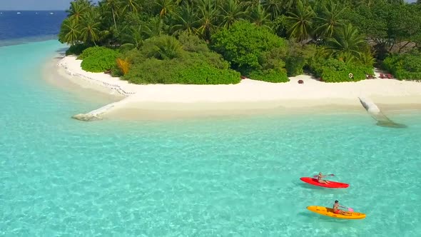 Aerial drone view of a man and woman couple kayaking around a tropical island